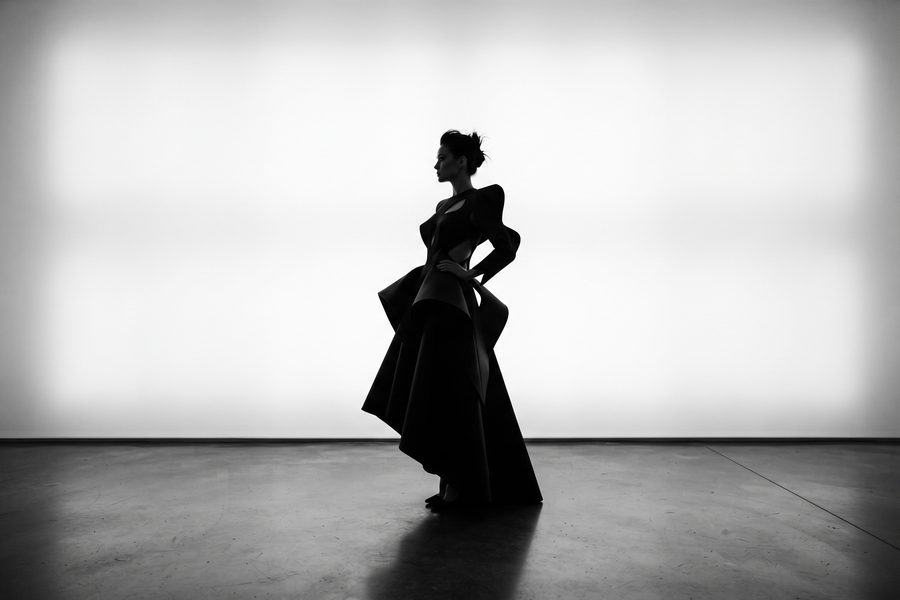 Dunkle Silhouette in einem weiten Kleid vor heller Studiowand