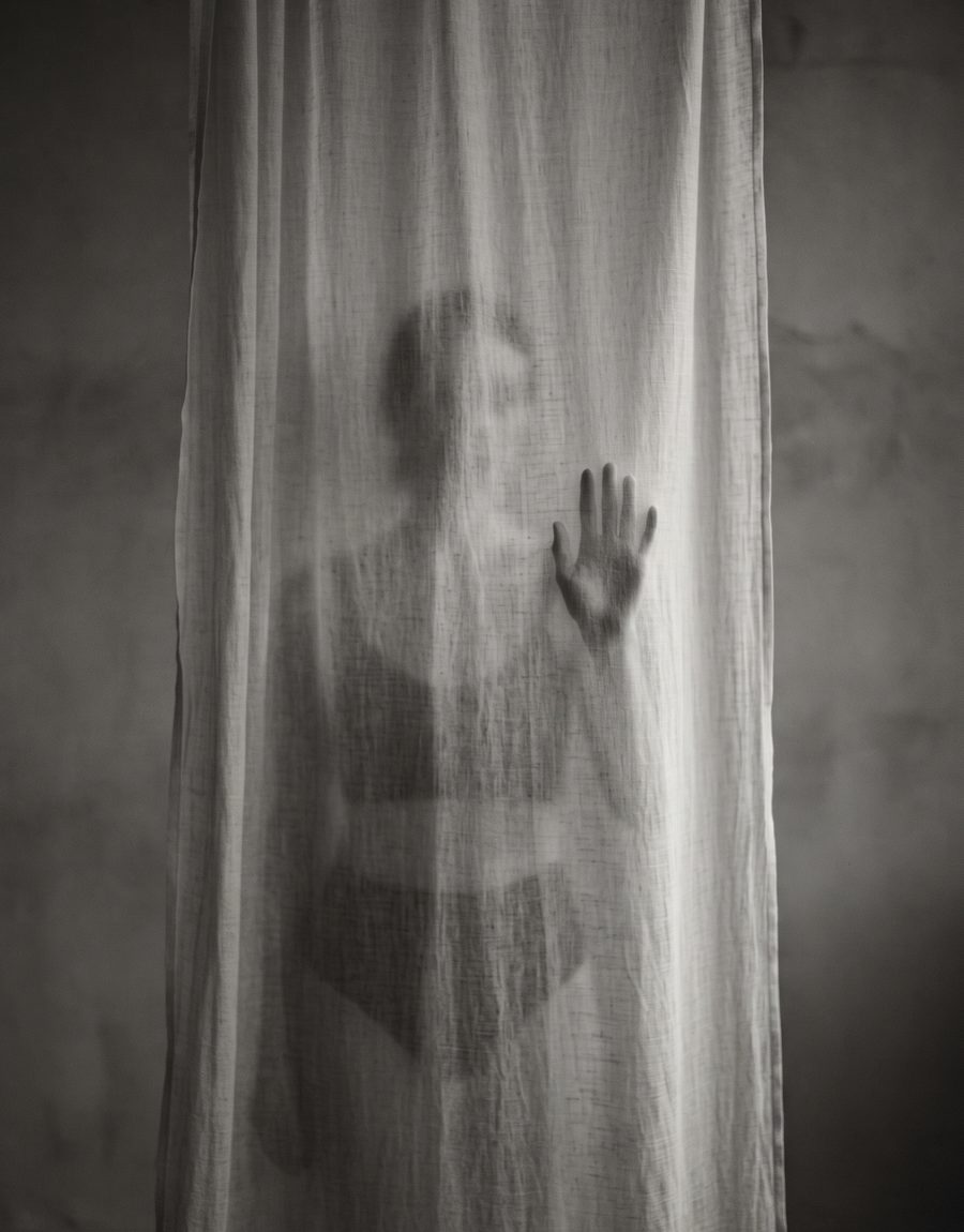 Silhouette hinter einem Vorhang, eine Hand gegen den Stoff gelegt